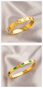 Vue détaillée de bracelets en acier titane doré avec zircons émeraude et motifs soleil