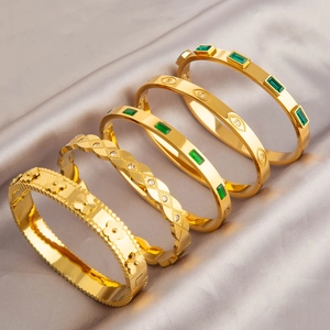 Cinq bracelets en acier titane doré aux motifs floraux et émeraudes sur soie