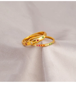 Detail van gouden sterring en dunne band met kleurrijke zirkoon op paarse zijde
