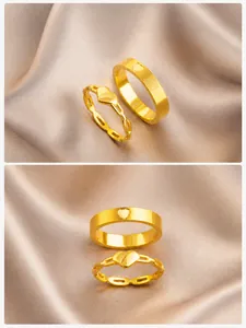 Detail of gold-plated hollow chain heart rings set on a grey silk fabric background