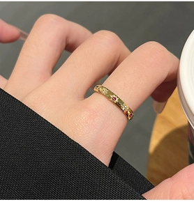 Detail van een dunne gouden ring met stergravures en gekleurde zirkonia aan de hand