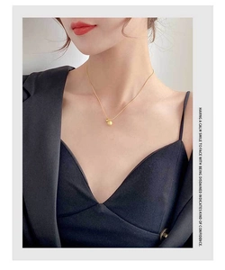 Close-up of a titanium steel choker featuring double golden beads on a delicate chain