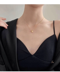 Close-up of matte and polished gold sphere pendants on a delicate titanium steel chain