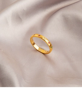 Macro-opname van gouden ring met kleurrijke zirkoon en stergravure op paars zijde