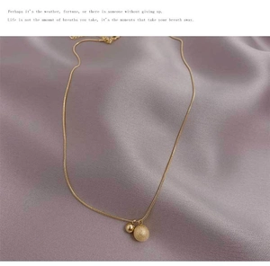 Detail of matte gold ball and polished bead on titanium steel minimalist necklace chain