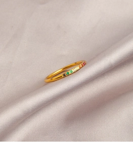 Detailopname van een gouden slanke ring met gekleurde zirkoon op zijden achtergrond