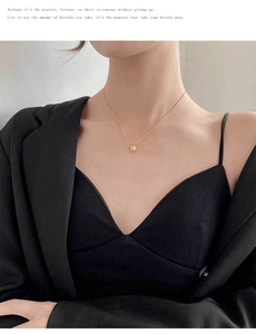 Close-up of a matte gold ball pendant on a fine titanium steel necklace worn on the neck