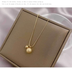 Detailed macro view of matte and polished gold sphere charms on a sleek snake chain