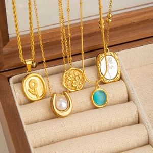 Elegante gouden titanium kettingen met parels en stenen op een houten sieradendoosje