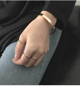 Close-up of polished rose gold titanium cuff bracelet and matching rings on model