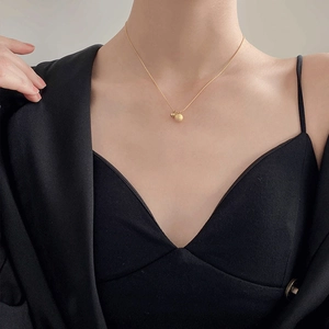 Minimalist matte and polished gold sphere pendant necklace worn on a black outfit