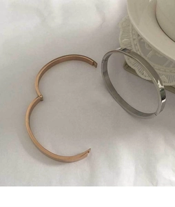 Polished stainless steel hinge bracelets in rose gold and silver on white fabric