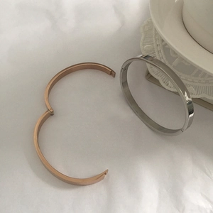 Minimalist titanium steel hinge bracelets in rose gold and silver finishes on a desk