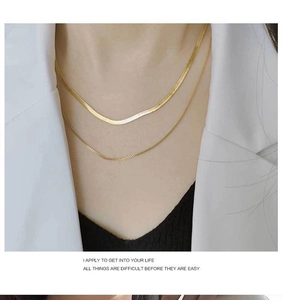 Détail d'un collier double rang en maille serpent dorée porté sur le cou du mannequin