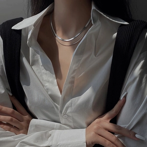 Collier double couche argenté à maille serpent porté par un mannequin de mode