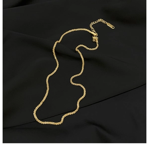 Detailed macro shot of golden wheat chain necklace with lobster clasp on silk background