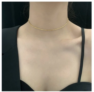 Detailed close-up of a shimmering gold woven chain necklace worn on a neck
