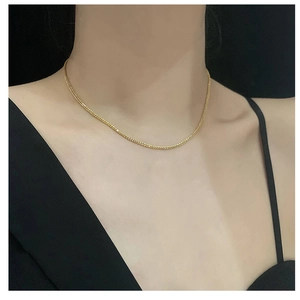 Close-up of golden titanium necklace showing popcorn chain texture on collarbone