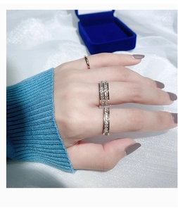 Detailopname van gestapelde roségouden titanium ringen met kristallen pavé op een blauwe trui