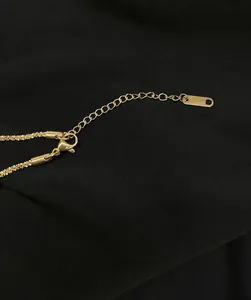 Close-up of gold titanium steel necklace showing lobster clasp and adjustable extension chain