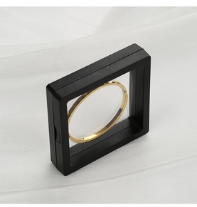 Primer plano del joyero cuadrado negro con película de PE, pulsera de oro y botón