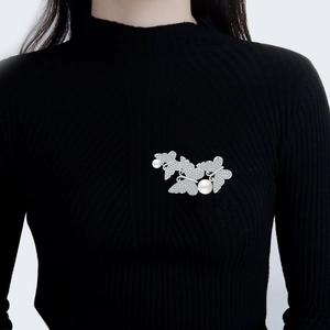 Elegant butterfly pearl brooch with sparkling zircons on a black sweater for women