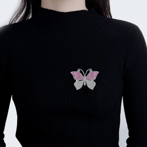 Elegant butterfly brooch with pink and white zircon crystals on a black knitted sweater
