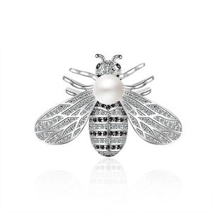 Broche abeille argentée avec zircons micro-pave et perle blanche sur fond réfléchissant