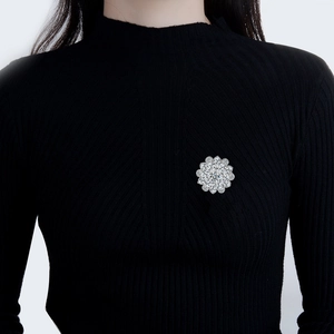 Elegant daisy flower brooch with sparkling cubic zirconia on a black sweater