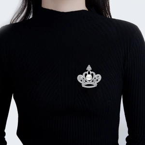 Elegant silver crown brooch with large pearl and sparkling zircon on black knitwear
