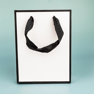 Minimalistische weiße Papiertüte mit schwarzem Rand und Seidengriffen für Luxus-Shopping