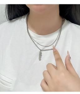 Close-up of double-layered titanium steel feather pendant necklace on a white t-shirt