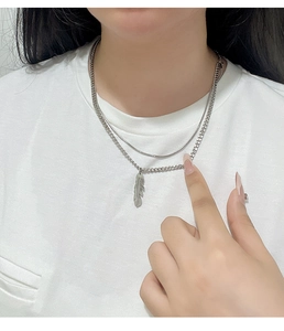 Detail of layered titanium steel necklaces with a textured silver feather pendant