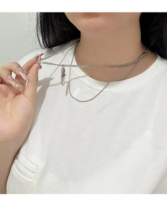 Macro shot of double layered titanium steel feather necklace on white cotton tee