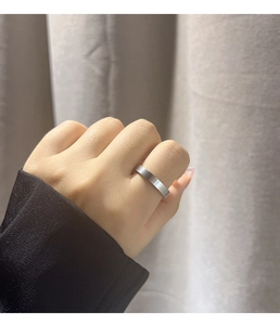 Nahaufnahme eines minimalistischen silbernen Edelstahl-Flachrings an einem Finger