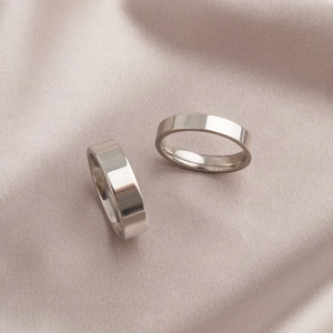 Minimalistische Ringe aus poliertem Titanstahl auf elegantem Seidenhintergrund
