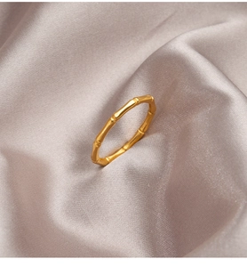 Macro detail of golden bamboo knot steel ring on luxurious silk fabric background