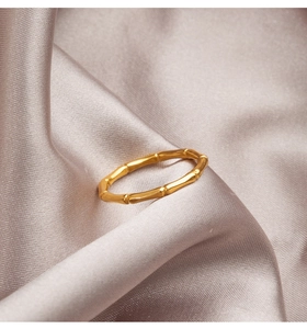 Macro shot of gold bamboo joint ring resting on elegant champagne silk fabric texture
