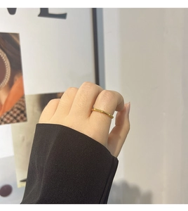 Close-up of golden bamboo joint ring on index finger with black blazer sleeve