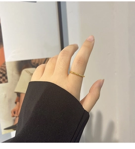 Detail view of a gold bamboo-style titanium steel ring worn on a woman's finger