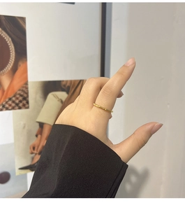 Detailed view of a gold bamboo-style titanium steel ring worn on a model's finger