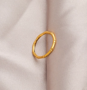 Macro shot of gold bamboo joint ring on pink silk fabric showing detailed metal texture