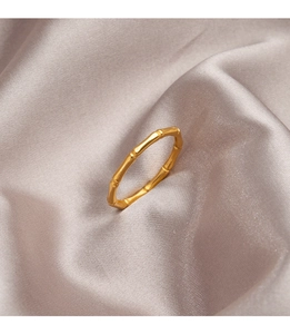 Macro shot of polished gold bamboo style titanium ring on elegant silk background