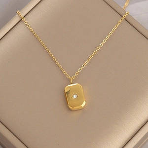 Close-up of gold rectangular pendant with starburst motif and cubic zirconia