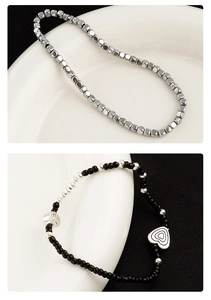 Detail van kralenarmband met zilveren kubussen, zwarte kralen en hartvormige bedels