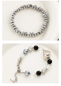 Detailweergave van zilveren kralenarmbanden met metalen harten en gemengde parelbedels