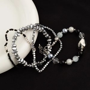 Minimalistische kralenarmbandset met zilveren kralen op een zwarte stoffen achtergrond