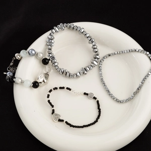 Set van vier gestapelde kralenarmbanden met hartjes in zilveren en zwarte tinten