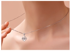 Gros plan d'un pendentif trèfle en argent avec topaze sur le cou d'une femme