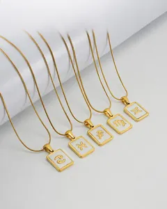 Macro detail of square 18K gold plated stainless steel zodiac pendants on white props